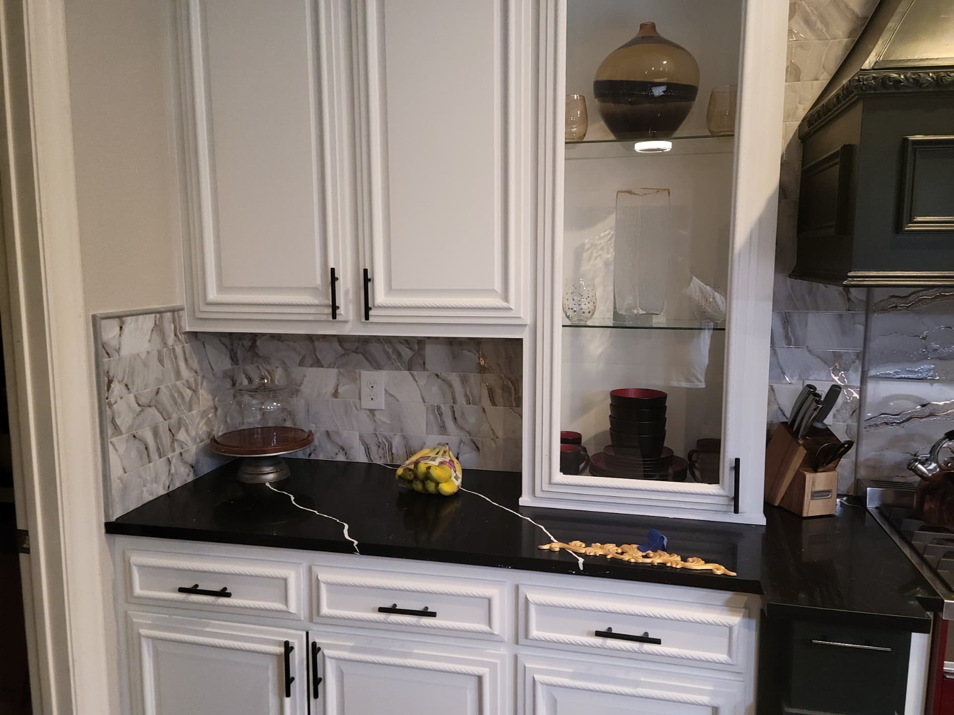 White cabinets with black counters and stone backsplash