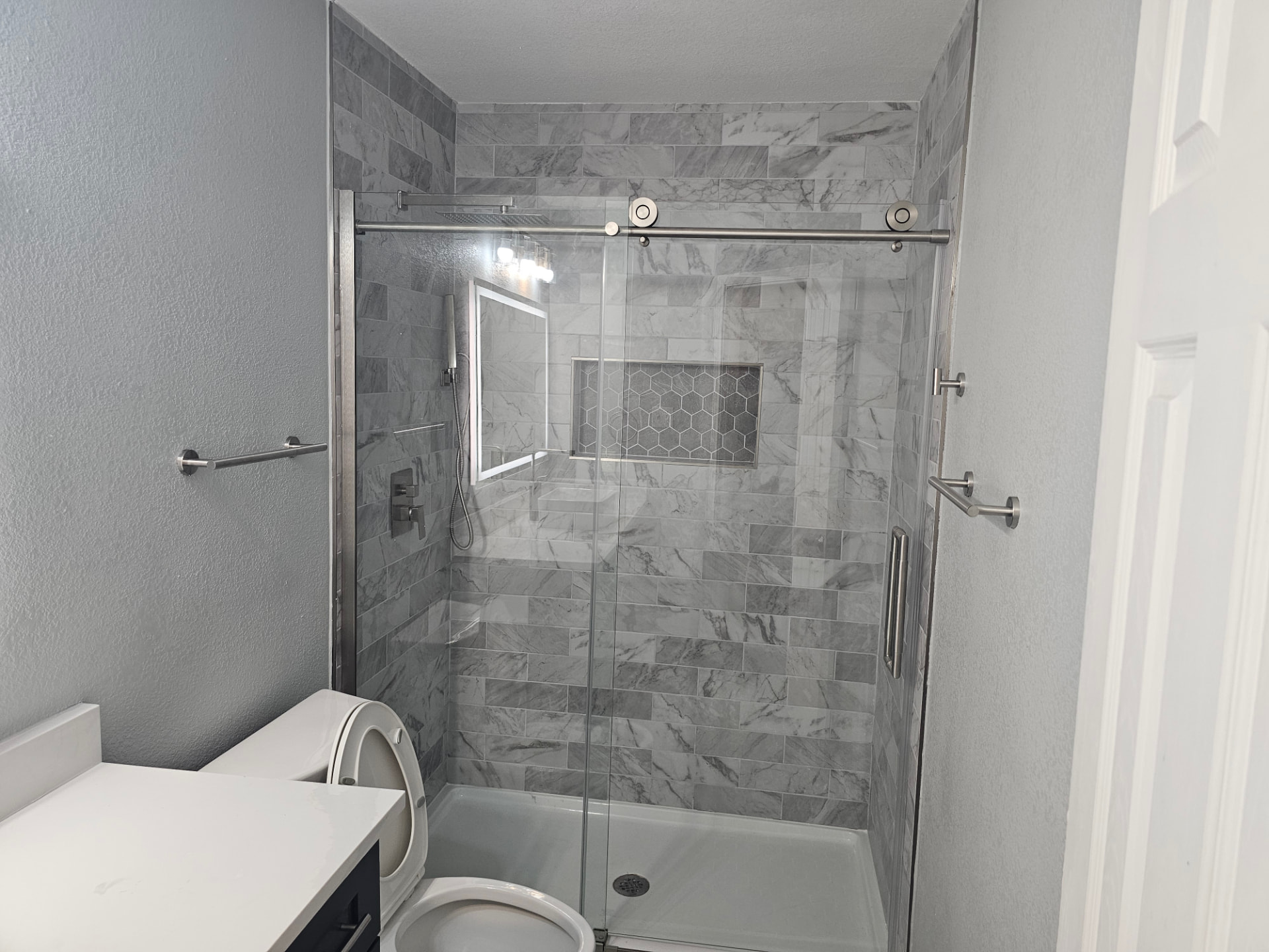 Finished bathroom with gray marble shower and glass sliding door
