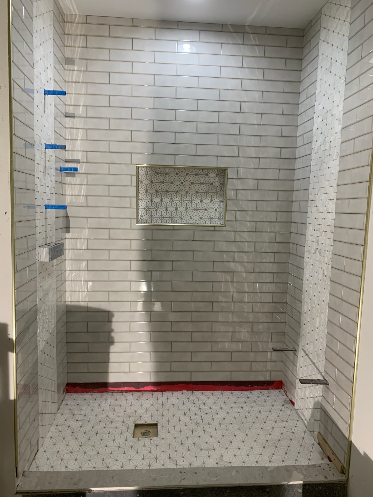Shower with white subway tile and a gold star-pattern mosaic niche